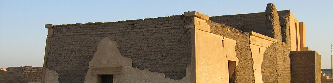 Mudbrick tomb architecture illuminated by the evening light of the desert necropolis.