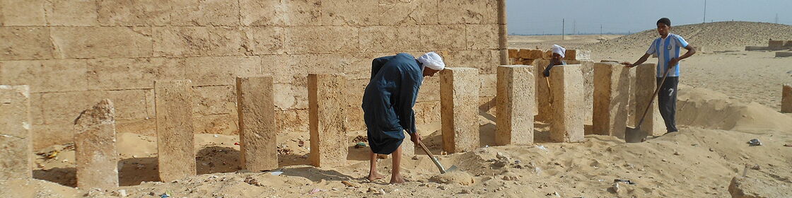 Local workers carefully clearing sand from architectural remains during archaeological excavations.