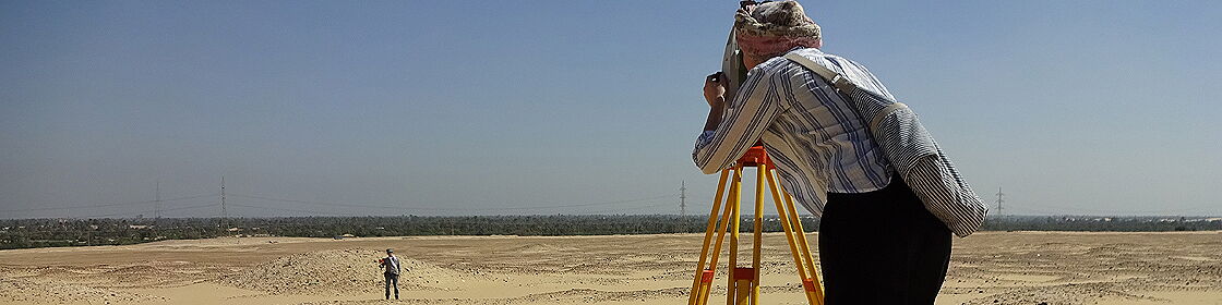 Archaeological survey using surveying equipment to document and map excavation areas.