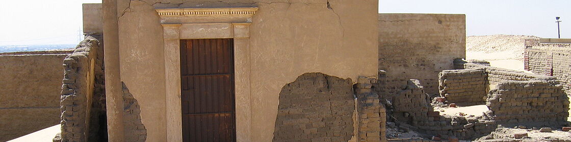 Architectural remains of mudbrick funerary structures shaped by centuries of occupation and desert conditions.